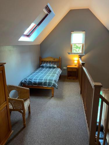 a attic bedroom with a bed and a window at The Wicket Cottage in Burlescombe