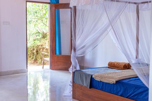 a bed with a canopy in a room with a window at Rainforest Soul Villa in Mederipitiya