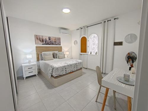 a white bedroom with a bed and a table at Casa Kevin in Puerto de Mogán