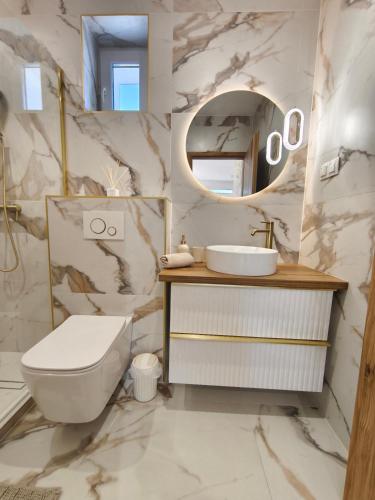 a bathroom with a sink and a toilet and a mirror at Prime Luxury Apartman in Mátészalka