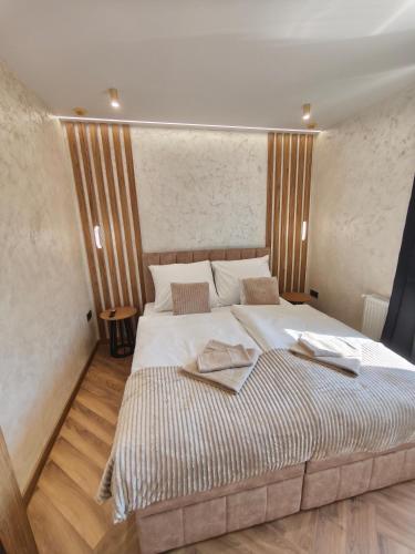 a bedroom with a large bed with two towels on it at Prime Luxury Apartman in Mátészalka