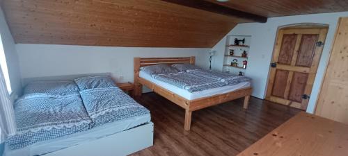 a bedroom with two beds and a wooden ceiling at Chalupa Krbálka in Jeseník