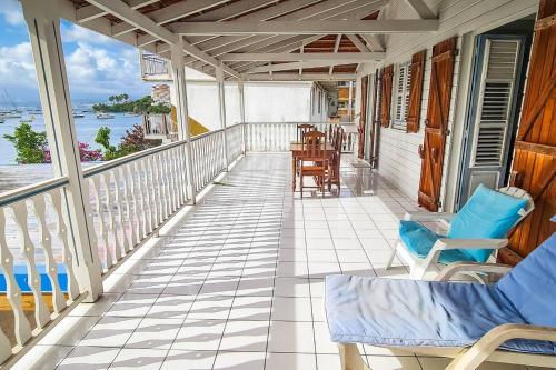 a balcony with chairs and tables and a view of the water at Villa bougainvillier in Les Trois-Îlets