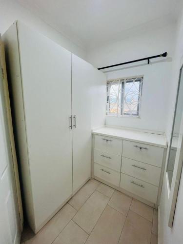 a kitchen with white cabinets and a window at Teiman Apartments in Teiman