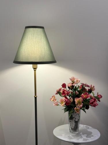 a vase of flowers sitting on a table next to a lamp at Apartmenthaus Döbeln Zentrum in Döbeln