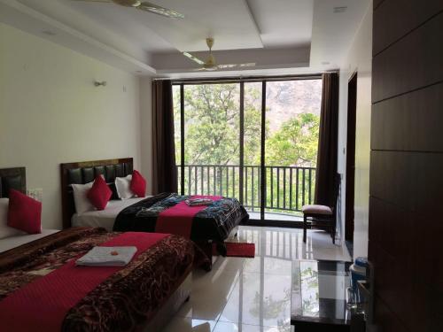 a hotel room with two beds and a balcony at Hotel Shri Mahavir in Chamoli