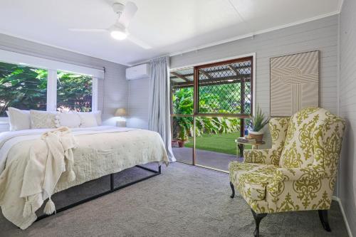 a bedroom with a bed and a chair and a window at The Hideaway in Bargara