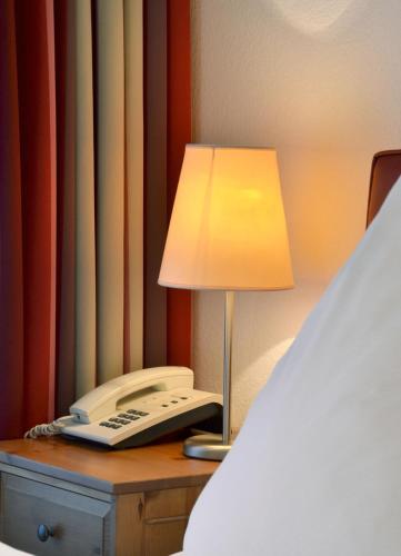 a telephone and a lamp on a desk next to a bed at Hotel im Kupferkessel in Cologne