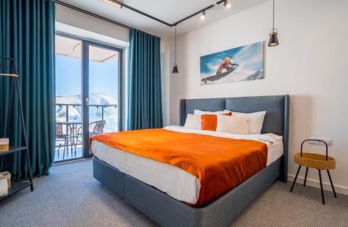 a bedroom with a bed with an orange blanket at New Gudauri Viva Seasons in Gudauri