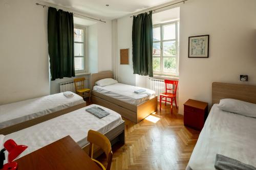 a room with three beds and a table and chairs at The Old Town Hostel-Villa Gradac in Dubrovnik