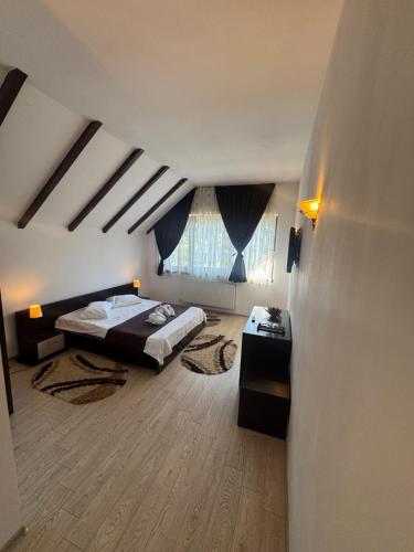 a bedroom with two beds and a large window at Hotel boutique Garden Resort by Brancoveanu in Moieciu de Jos