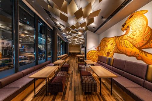 a row of tables and benches in a restaurant with a mural at Hotel Vista Osaka Namba in Osaka