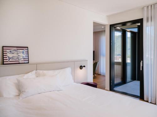 a bedroom with a white bed and a large window at THE FLAG Lugano - Self Check-in in Massagno