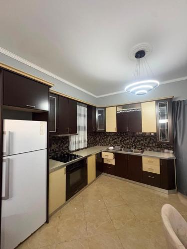 a large kitchen with a white refrigerator and cabinets at Casa bushi in Kamëz