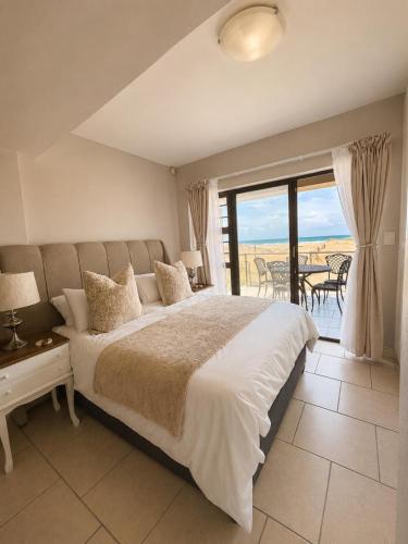 a bedroom with a large bed and a balcony at Klein paradys Jeffreys bay in Jeffreys Bay
