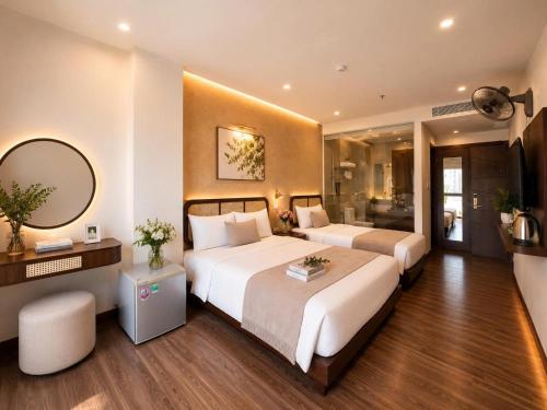 a hotel room with two beds and a mirror at LAVISH OCEAN INN Đà Nẵng in Danang