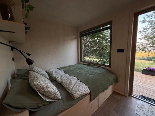 a bed in a small room with a window at Maringotka Na mezi in Maršovice