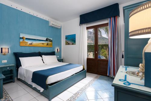 a blue bedroom with a bed and a window at Athena Bed & Breakfast in San Vito lo Capo