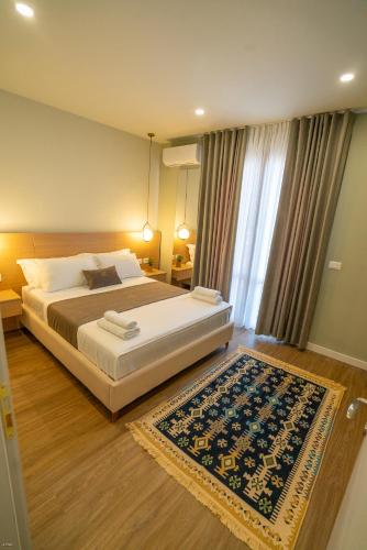 a bedroom with a large bed and a rug at Lùmar Hotel in Vlorë