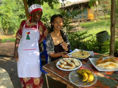 two women standing in front of a table with food at Arbaminch eco campsite and lodge in Ārba Minchʼ
