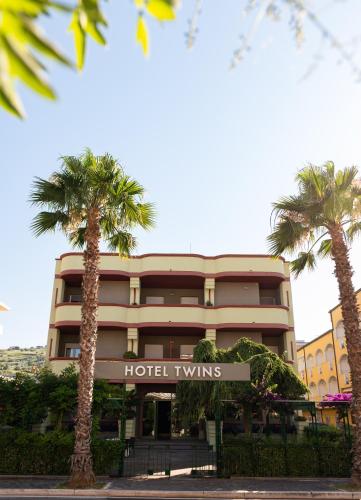 a hotel with palm trees in front of a building at Hotel Twins in Vasto