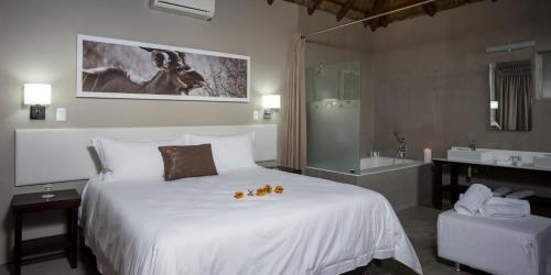 a bedroom with a large white bed and a bathroom at Monate Game Lodge in Modimolle
