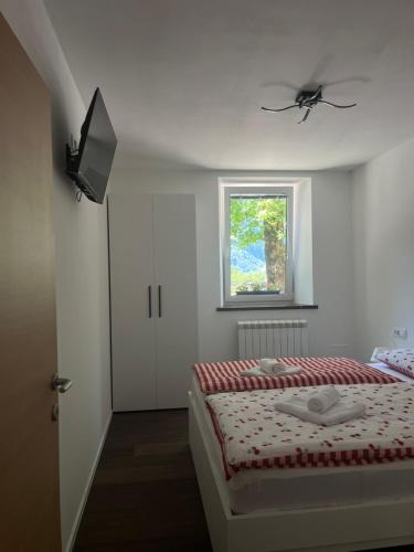 a white bedroom with a bed and a window at Apartma 35 in Soča