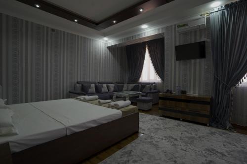 a bedroom with a bed and a couch and a television at Hotel Ayyub Sultan in Urganch