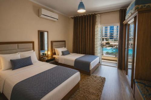 a hotel room with two beds and a balcony at ابراج الداون تاون العلمين الجديده Luxury Apartment In Downtown New Alamein in Ad Darāzīyah