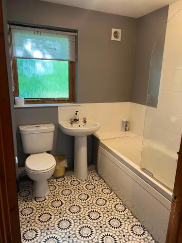 a bathroom with a toilet and a sink and a tub at The Wicket Cottage in Burlescombe