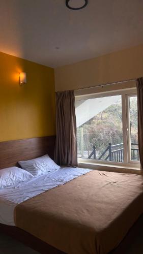 a bedroom with a large bed and a window at Elysian Villa by Hostel Jerusalem in Kodaikānāl