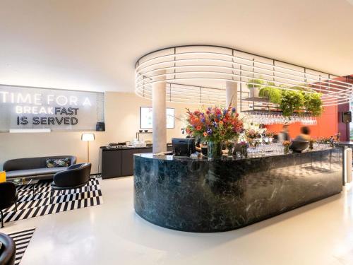 a lobby with a counter with flowers on it at ibis Brussels Centre Chatelain in Brussels