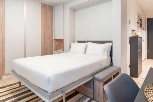 a bedroom with a large white bed and a chair at City Pop 2Night Geneva - Self check-in in Geneva