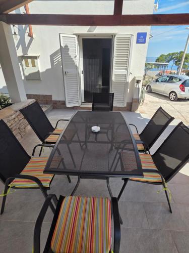a glass table and chairs on a patio at Kuća za odmor Neva in Nečujam