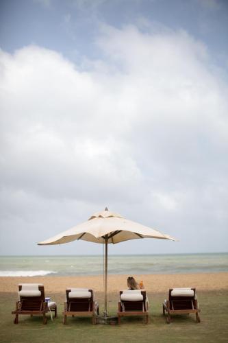 two chairs and an umbrella on a beach at Anantaya Resort & Spa Chilaw in Chilaw