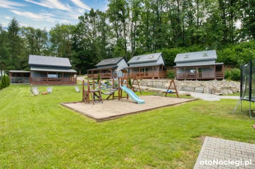 a playground in front of a log cabin at Domki przy Skarpie in Lądek-Zdrój