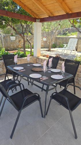 a black table and four chairs on a patio at Kuća za odmor Neva in Nečujam