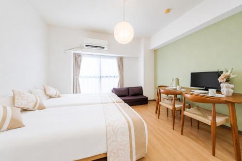 a bedroom with a bed and a desk and a television at 宇都宮ハウスシラユリ in Utsunomiya