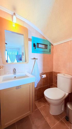 a bathroom with a toilet and a sink and a mirror at Aurora Maris Maisonette in Possidi