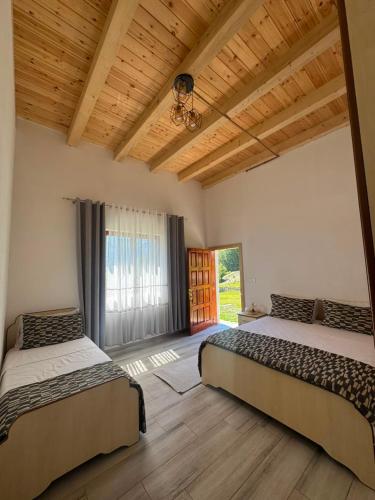 a bedroom with two beds and a large window at Guesthouse Bjeshket E Arta in Lëpushë