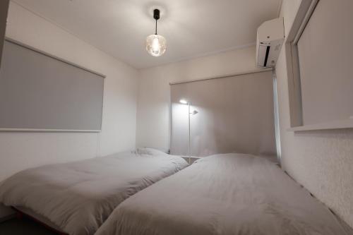 two beds in a room with white walls at 一軒家貸切 THREE FIELD Kobe Nakayamate in Kobe