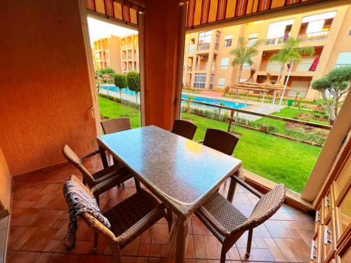 a table and chairs on a balcony with a view of a yard at Reco flores PALM in Ben Slimane