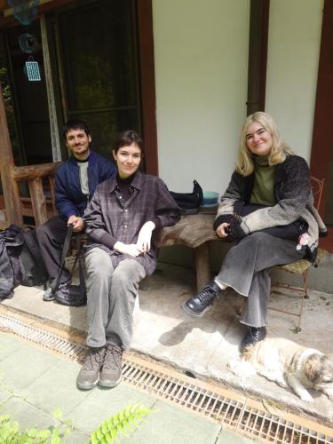Drei Personen sitzen mit einem Hund auf einer Bank in der Unterkunft COZY Inn Free Shuttle service in Nikko