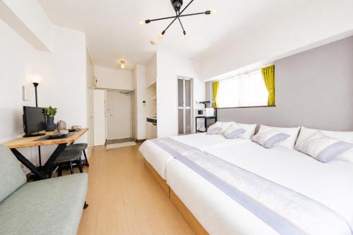 a white bedroom with a large bed and a desk at 宇都宮ハウスリリー in Utsunomiya
