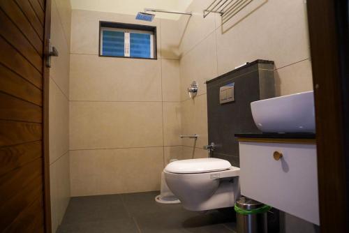 a bathroom with a white toilet and a sink at Skyleaf Resort in Meenangadi
