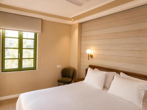 a bedroom with a bed and a window and a chair at Athena Collection in Kefalos