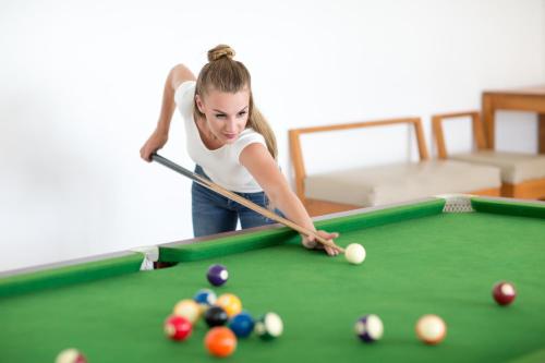 a woman playing pool with a cue on a pool table at Anantaya Resort & Spa Chilaw in Chilaw