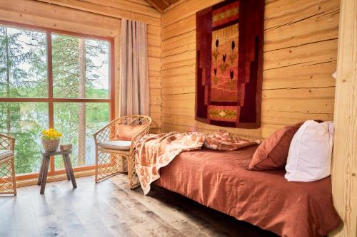 a bedroom with a bed in a wooden room with a window at Forest Cabin Ainola with Lake View next to Nuuksio National Park in Otalampi
