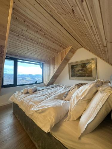a large bed in a room with a wooden ceiling at Dealul Notarasului Retreat in Gara Piatra Craiului
