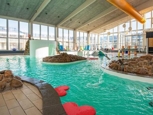 a pool with rocks in the water in a building at Premium apartment with loft in holiday park in Ringkøbing